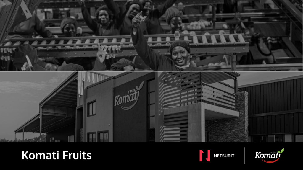 Group of workers on a fruit processing line inside a Komati Fruits facility, smiling and raising hands in celebration.
