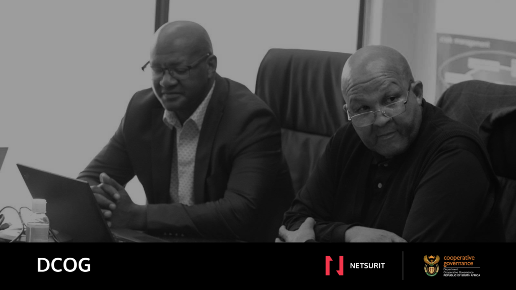 Two DCOG officials working at a laptop
