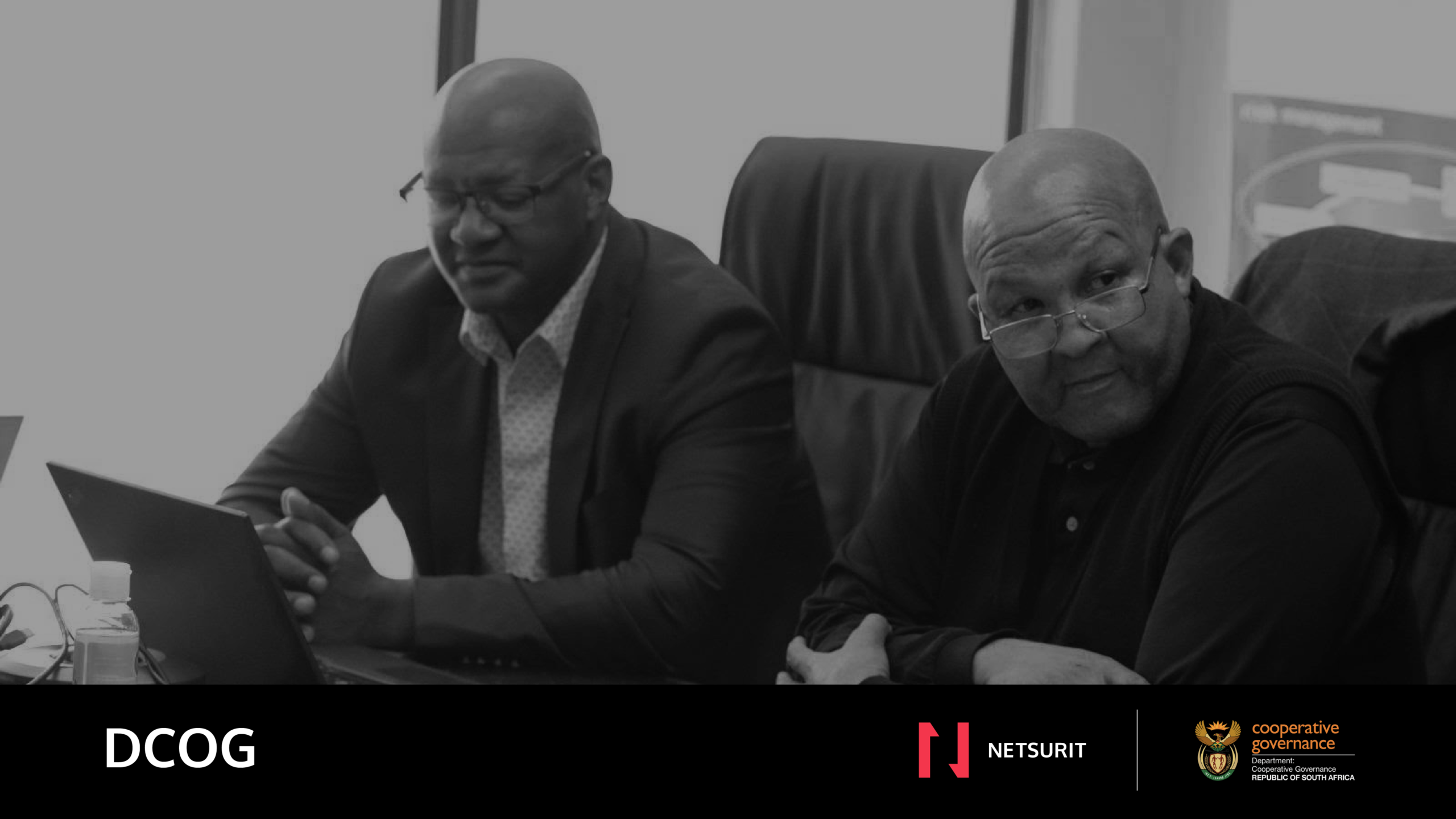 Two DCOG officials working at a laptop